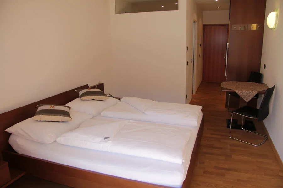 Pokój dwuosobowy: część sypialna i kącik wypoczynkowy · Garni Hotel Am Burghügel