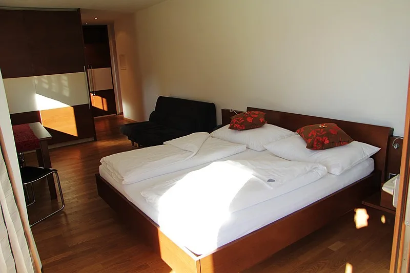 Pokój rodzinny: łóżko podwójne i drewniane meble · Garni Hotel Am Burghügel